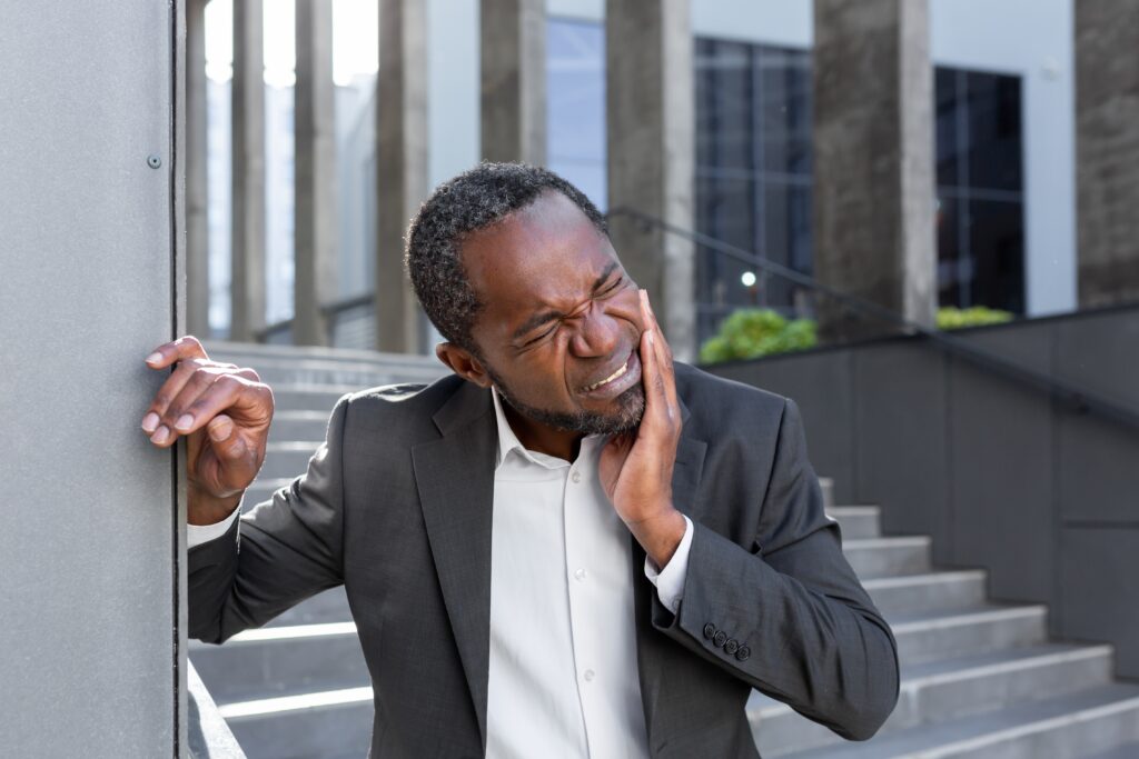 man in a suit suffering from jaw pain, possible sign of a dental emergency